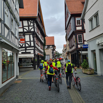 etwa 12 Radfahrer*innen in neongelben Warnwesten schieben ihre Räder die Obergasse in Alsfeld hoch