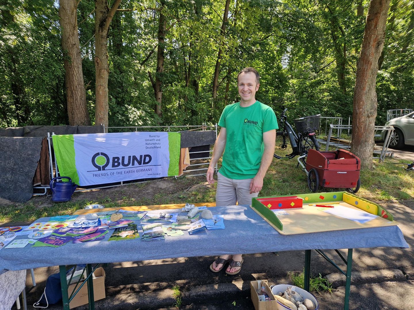 männliche Person hinter Infostand mit flyern und Broschüren